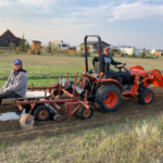 Summer students using tractor and rototiller to plant trees