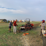 Four summer students preparing to use the tractor to lay tree mulch