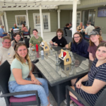 Eight summer students sitting around restaurant table for group photo