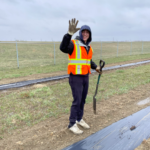 Summer student tree planting in rain, smiling and holding shovel