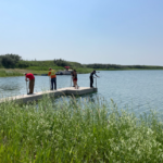 Four summer students adjusting dock placement on lake