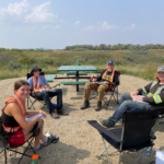 Four summer students smiling for photo while sitting in chairs learning about recreational trails